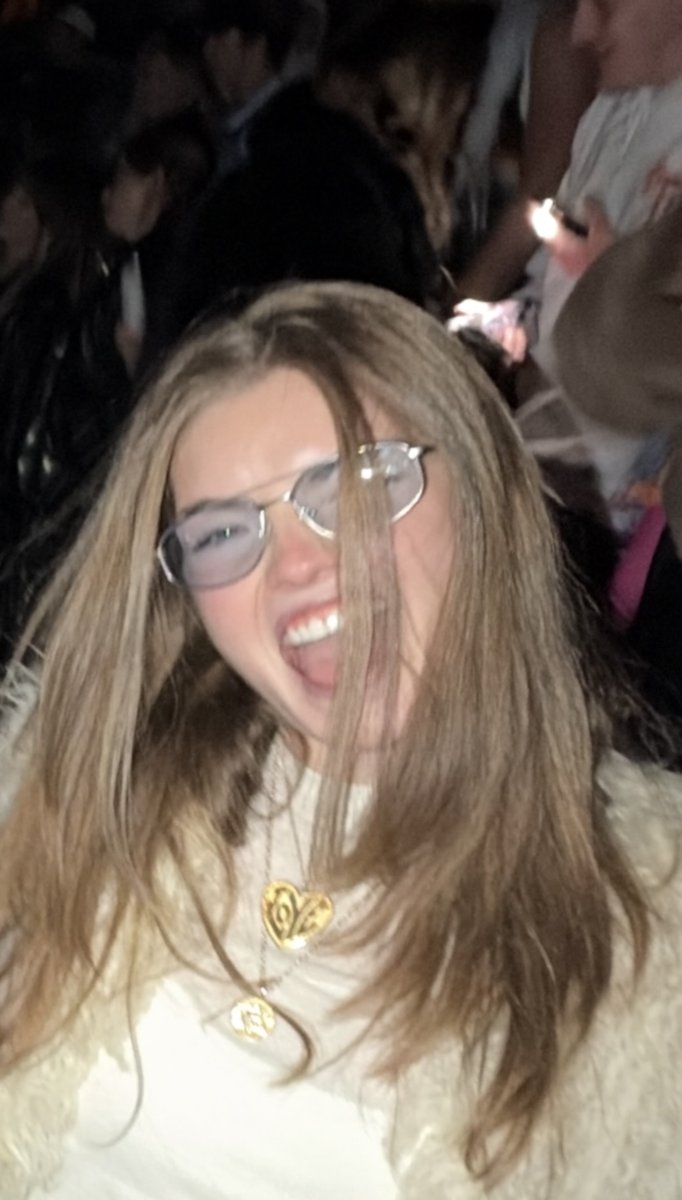 Molly in a fur coat and blue tinted glasses, mouth wide open mid scream.