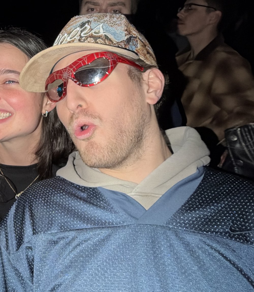 Zack in red Spider-Man sunglasses and a camo hat, mid duck face.